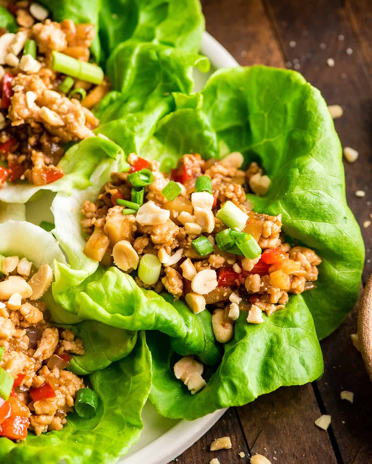 Asian Chicken Lettuce Wraps (better than P.F. Chang's)! A quick, easy, healthy and delicious dinner or appetizer! These lettuce wraps are our favorite! Step-by-step recipe video! #lettucewraps #pfchangs #glutenfree #dairyfree #easydinner #healthyrecipe #asianlettucewraps up close overhead view of an Asian chicken lettuce wrap on a plate