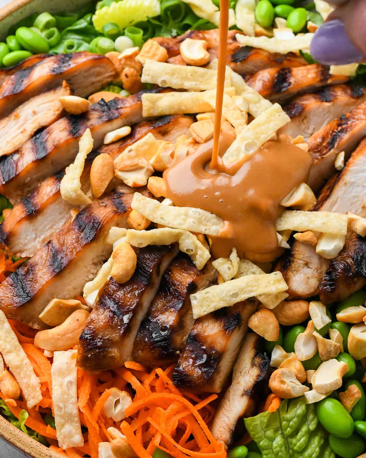 peanut dressing being poured onto Asian Chicken Salad