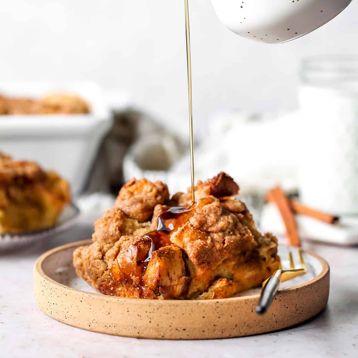 syrup being poured over a serving of Overnight French Toast Casserole on a plate