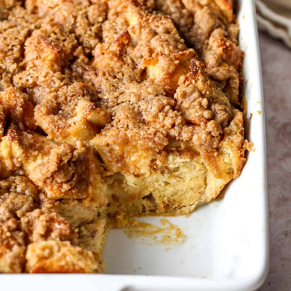 The best Baked French Toast Casserole recipe is an easy & delicious breakfast. French bread is combined with a sweet vanilla egg & milk mixture and topped with a buttery streusel topping. This overnight French toast casserole is made at night and baked in the morning so it's easy to prepare and enjoy! overnight french toast casserole in a baking dish with a piece cut out of it