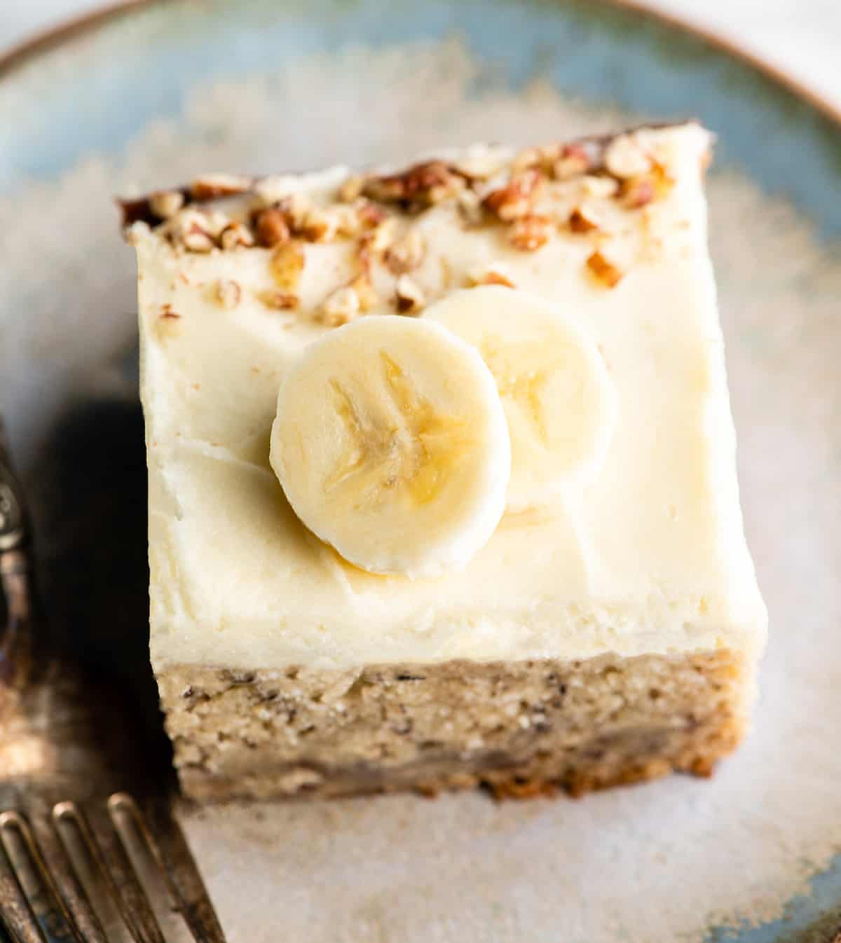 This is the best banana cake recipe ever! It's easy to make (no mixer required), moist, loaded with bananas and topped with a delicious cream cheese frosting. overhead view of a piece of banana cake