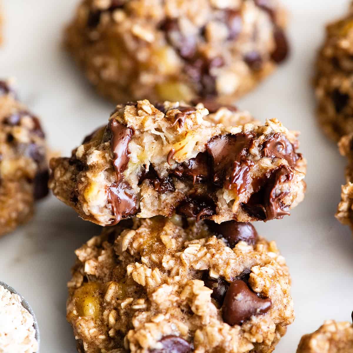 These banana oatmeal cookies are easy to make with a few simple ingredients in 20 minutes. Banana oat cookies are a delicious breakfast, snack or healthy dessert - add chocolate chip or your favorite mix-ins to make them extra-special! front photo of a Banana Oatmeal Cookie with a bite taken out of it