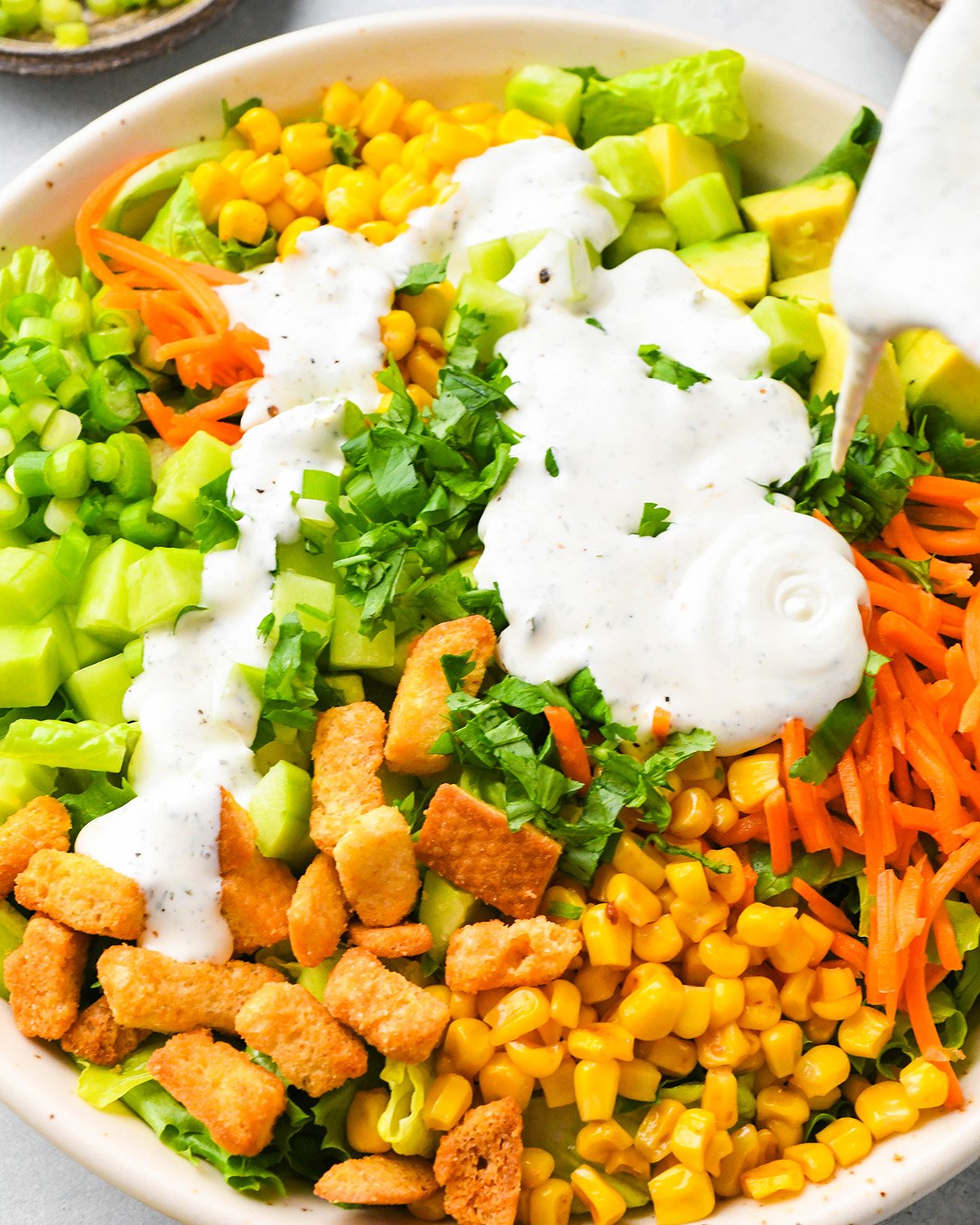 dressing being poured over BBQ Chicken Salad