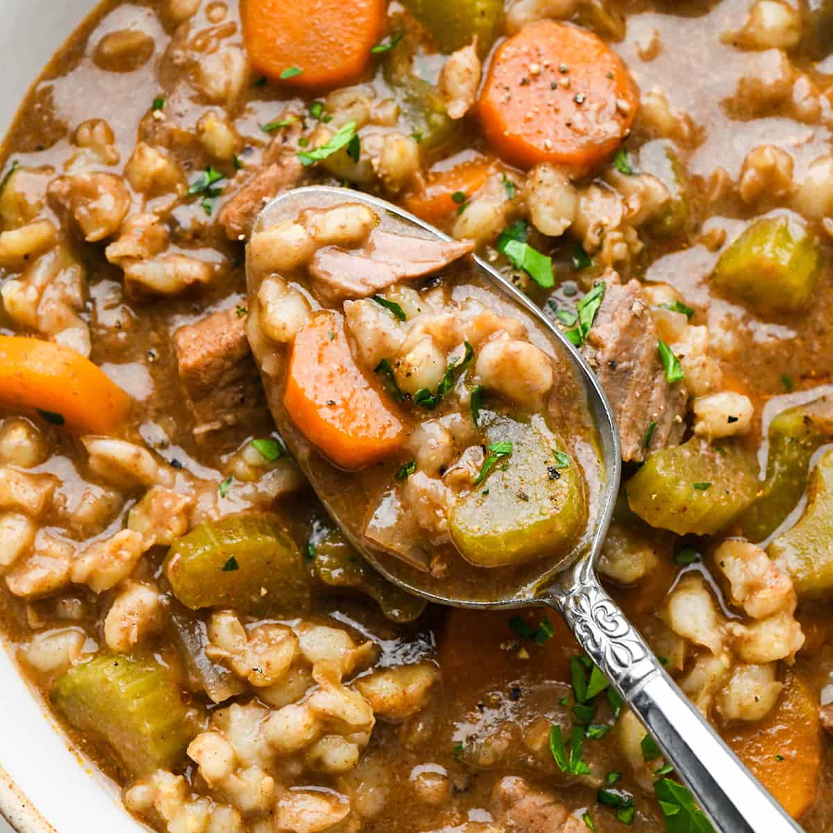 a spoon taking a scoop of Beef Barley Soup
