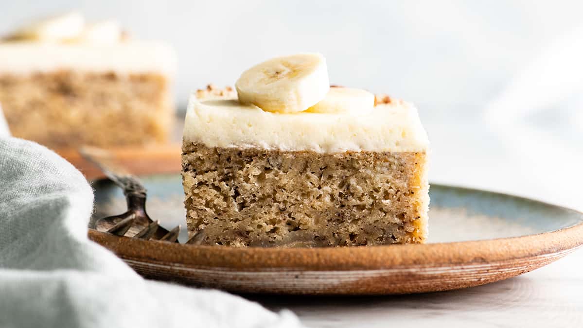 front view of a slice of banana cake with cream cheese frosting