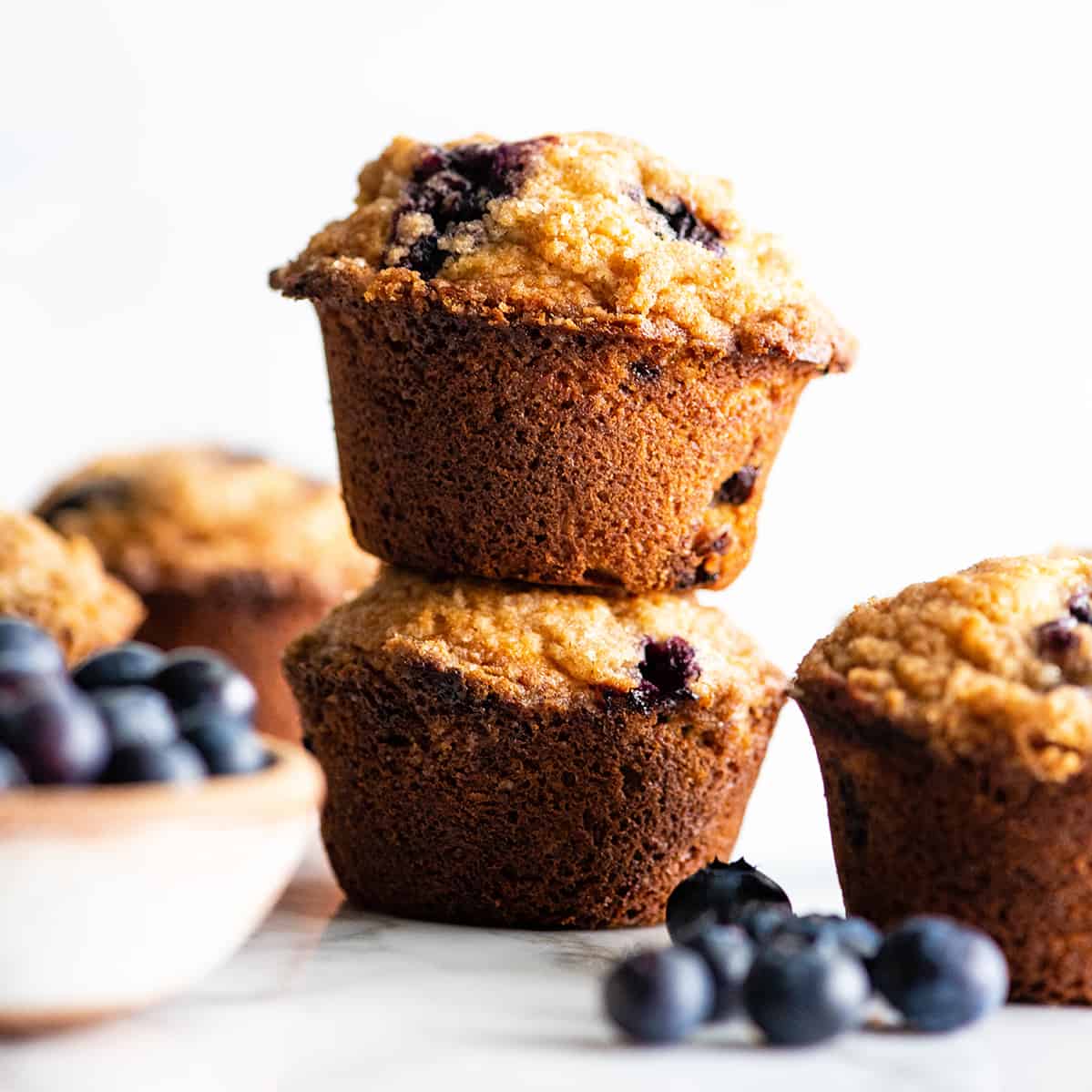 These are the best blueberry muffins ever! This blueberry muffin recipe results in moist, buttery blueberry muffins with a perfect texture that are loaded with fresh blueberries and topped with a crumb topping. They're easy to make in only 30 minutes and no mixer required! #blueberrymuffins #muffins #recipe #joyfoodsunshine #breakfast #brunch front view of two blueberry muffins stacked on each other