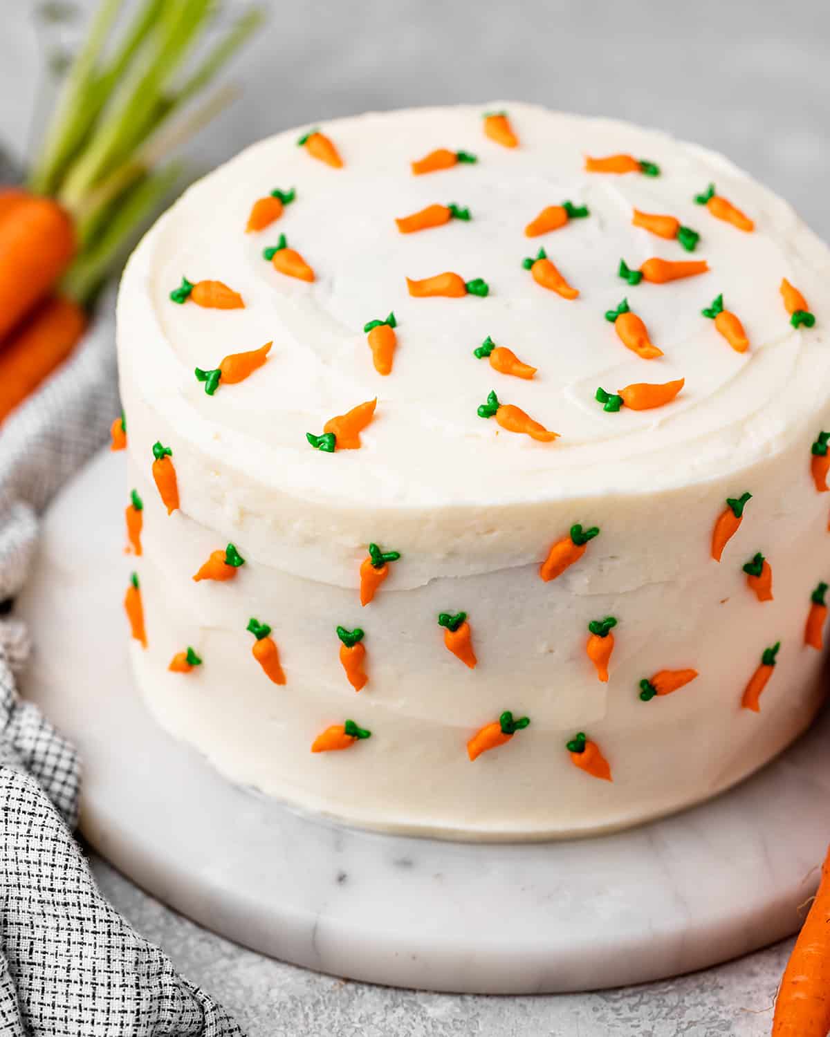 a whole carrot cake with cream cheese frosting and tiny frosting carrots all around it