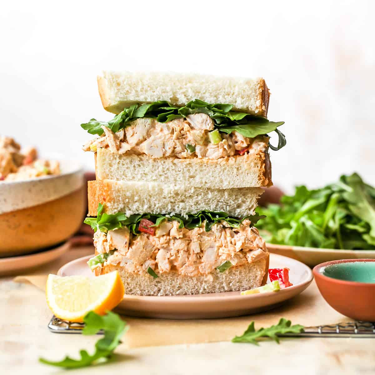 This Chicken Salad Recipe is easy to make with only a handful of simple ingredients. Serve as chicken salad sandwiches or on top of a bed of greens for a delicious, flavorful and light summertime meal! Watch the video and follow our step-by-step instructions to learn how to make chicken salad at home! front view of two halves of a chicken salad sandwich stacked