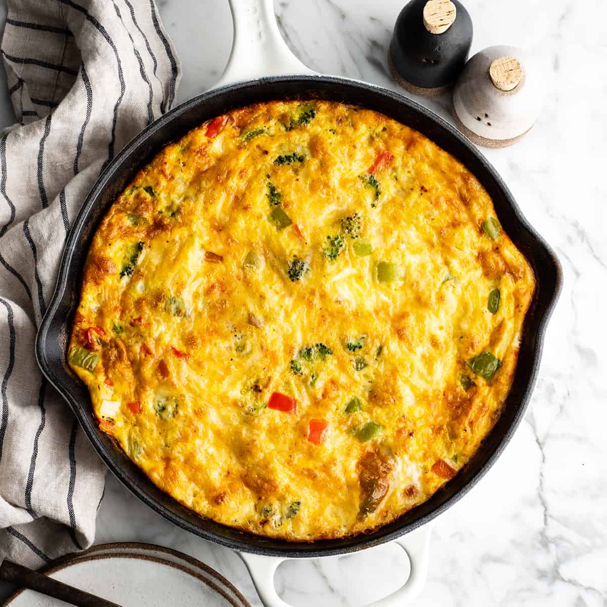 This easy Frittata Recipe is the perfect quick & healthy dinner, breakfast or brunch! Follow our step-by-step instructions and watch the video to learn how to make either a vegetable frittata or a frittata with bacon! overhead view of a vegetable frittata in a cast iron skillet