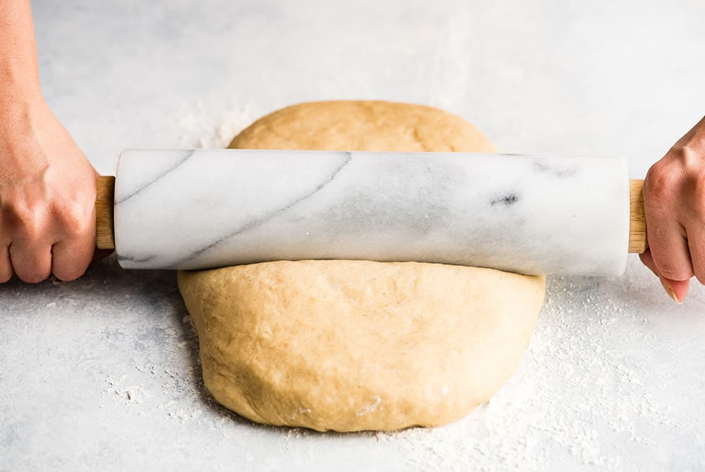 This is the Best Homemade Cinnamon Rolls Recipe EVER! These gooey cinnamon rolls are even better than Cinnabon cinnamon rolls, and are topped with a delicious cream cheese frosting! They're easy to make and can be prepared the day before and left to rise overnight in the refrigerator. front photo of hands rolling cinnamon roll dough