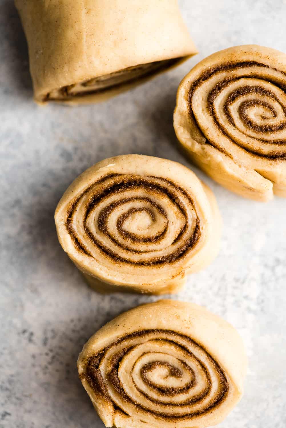 This is the Best Homemade Cinnamon Rolls Recipe EVER! These gooey cinnamon rolls are even better than Cinnabon cinnamon rolls, and are topped with a delicious cream cheese frosting! They're easy to make and can be prepared the day before and left to rise overnight in the refrigerator. overhead photo showing how to make cinnamon rolls - dough being cut into rolls