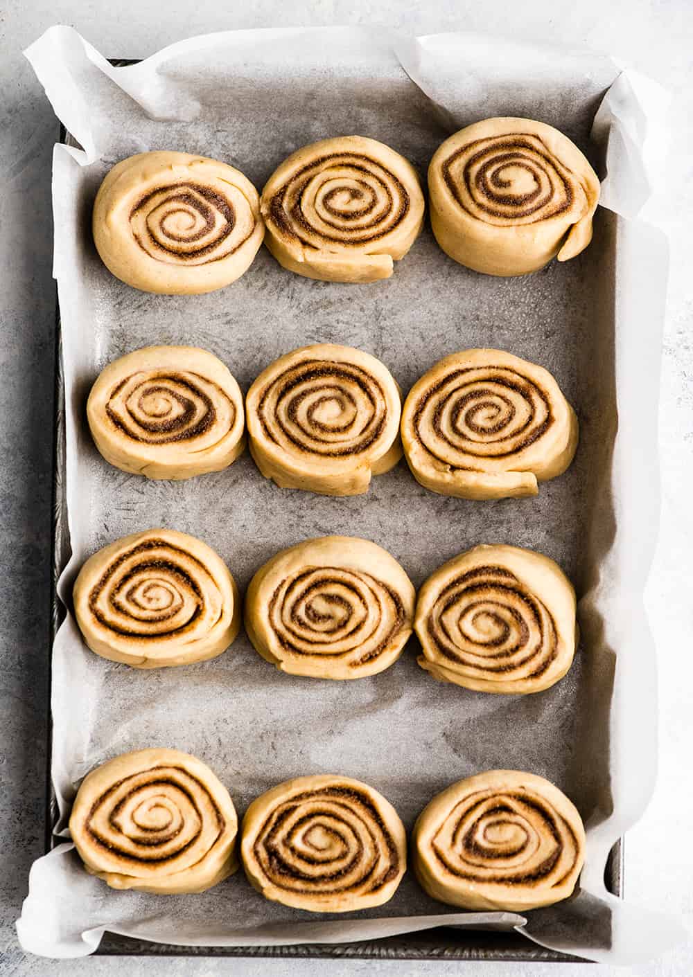 This is the Best Homemade Cinnamon Rolls Recipe EVER! These gooey cinnamon rolls are even better than Cinnabon cinnamon rolls, and are topped with a delicious cream cheese frosting! They're easy to make and can be prepared the day before and left to rise overnight in the refrigerator. Overhead photo showing how to make cinnamon rolls - rolls in baking pan before rising