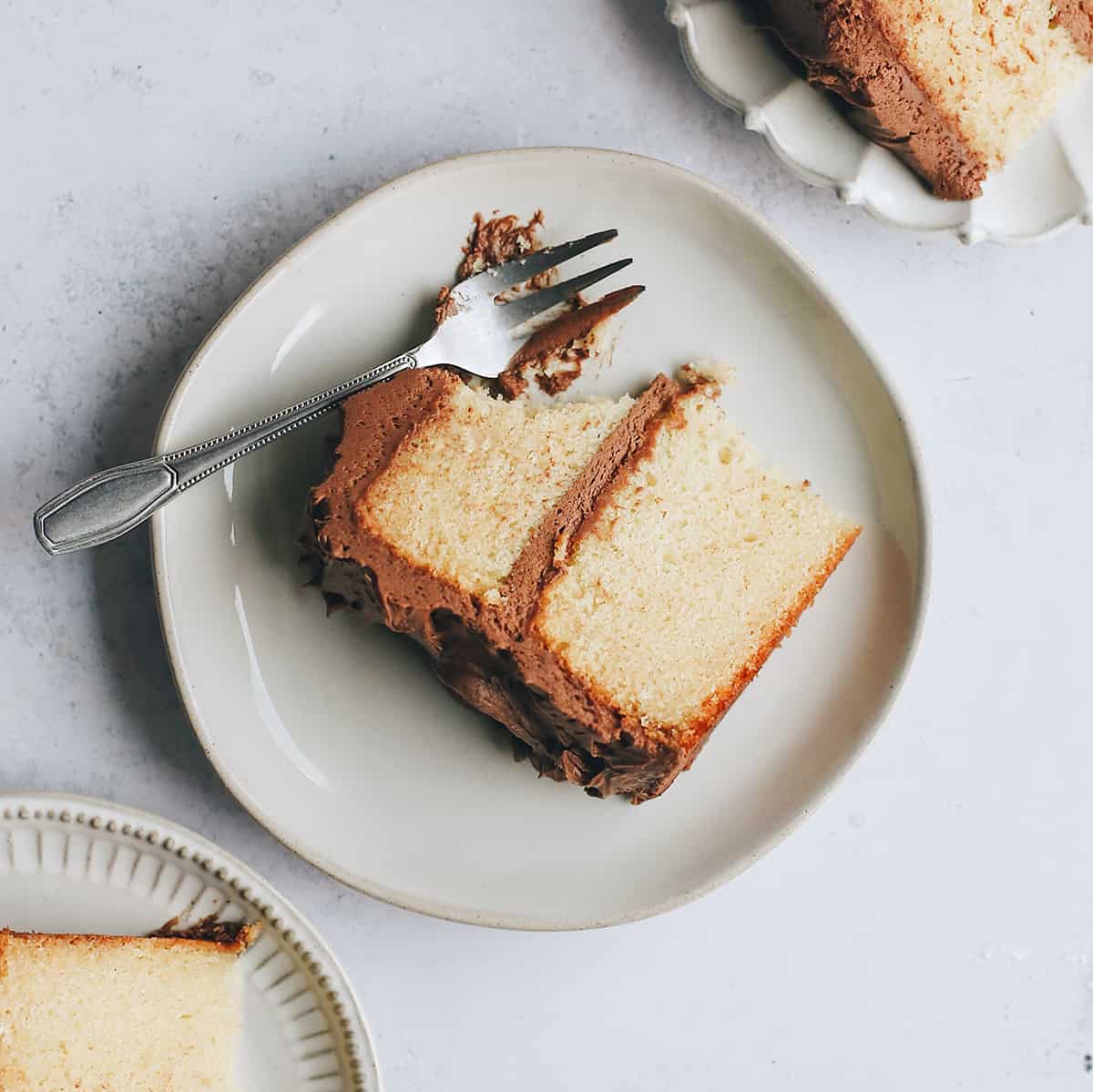 3 plates with slices of Yellow Cake on them, one with a fork and a bite taken out of it