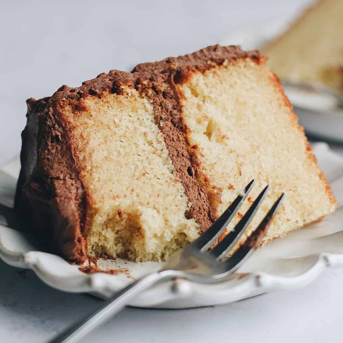 a slice of yellow cake on a plate with a fork and a bite taken out of it