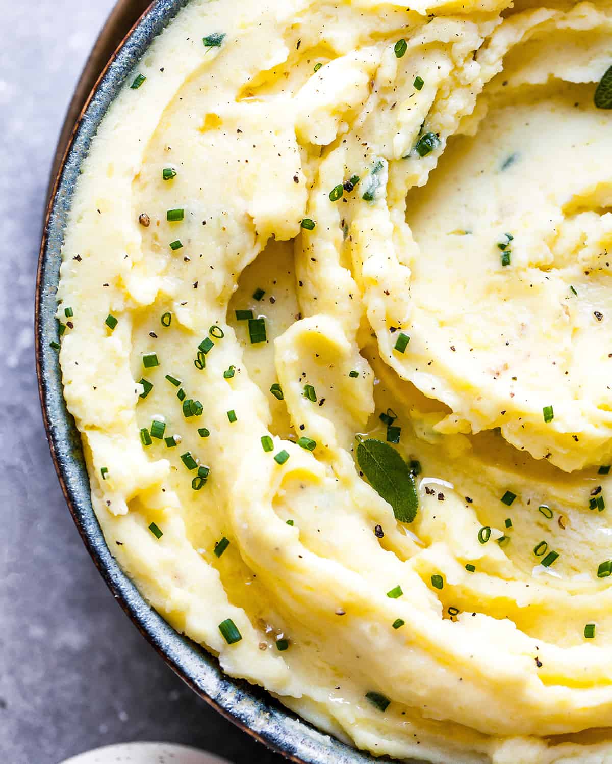 These herb-infused garlic mashed potatoes are the best mashed potatoes you will ever eat. They are creamy, fluffy buttery and so insanely delicious you will never make another mashed potatoes recipe again. Plus they're easy to make and can be prepared ahead of time! Overhead view of mashed potatoes in a bowl topped with fresh herbs