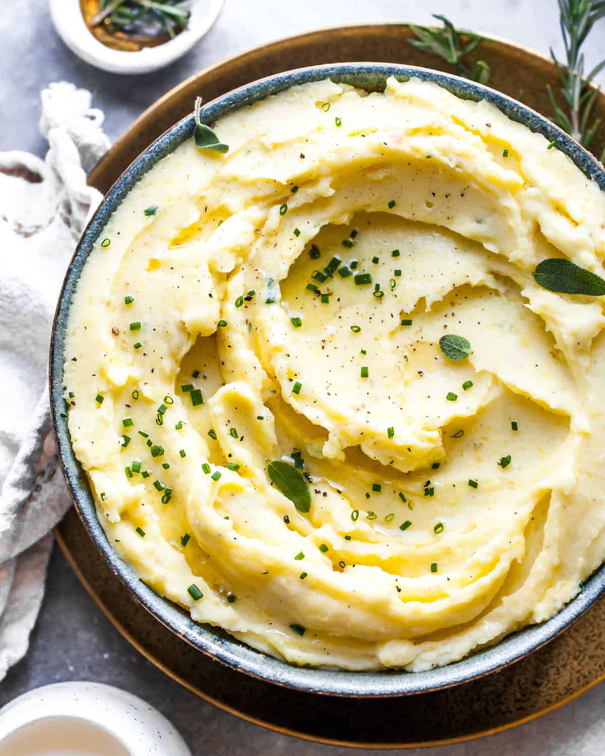 These herb-infused garlic mashed potatoes are the best mashed potatoes you will ever eat. They are creamy, fluffy buttery and so insanely delicious you will never make another mashed potatoes recipe again. Plus they're easy to make and can be prepared ahead of time! Overhead view of mashed potatoes in a bowl topped with fresh herbs