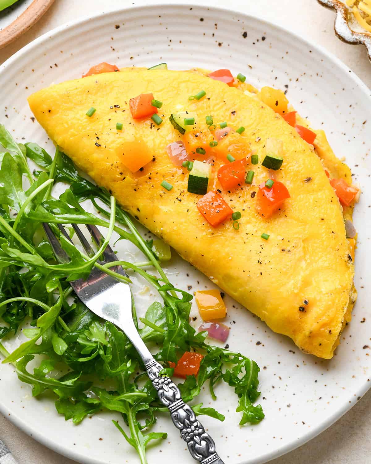 a vegetable omelette on a plate with a side of arugula