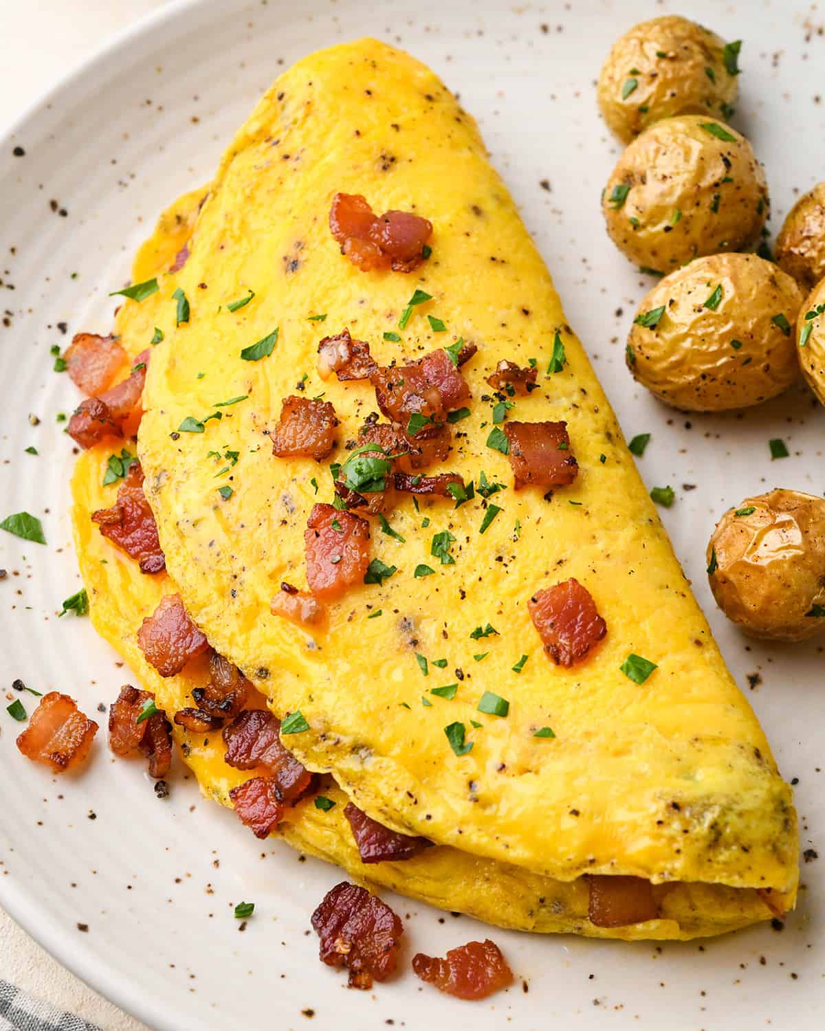 an omelette with bacon, herbs and a side of potatoes.
