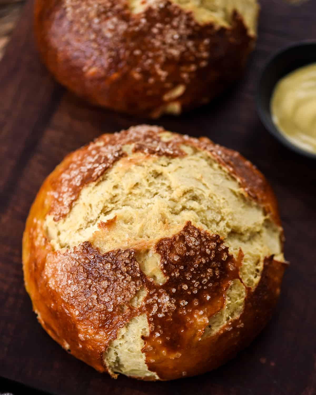 The BEST Homemade Pretzel Bread (or Pretzel Rolls) recipe ever. Seriously, once you make this you will never be able to eat store-bought pretzel bread again! It's dense, soft, chewy, buttery, salty and irresistibly delicious. Overhead view of two loaves of homemade pretzel bread on a cutting board