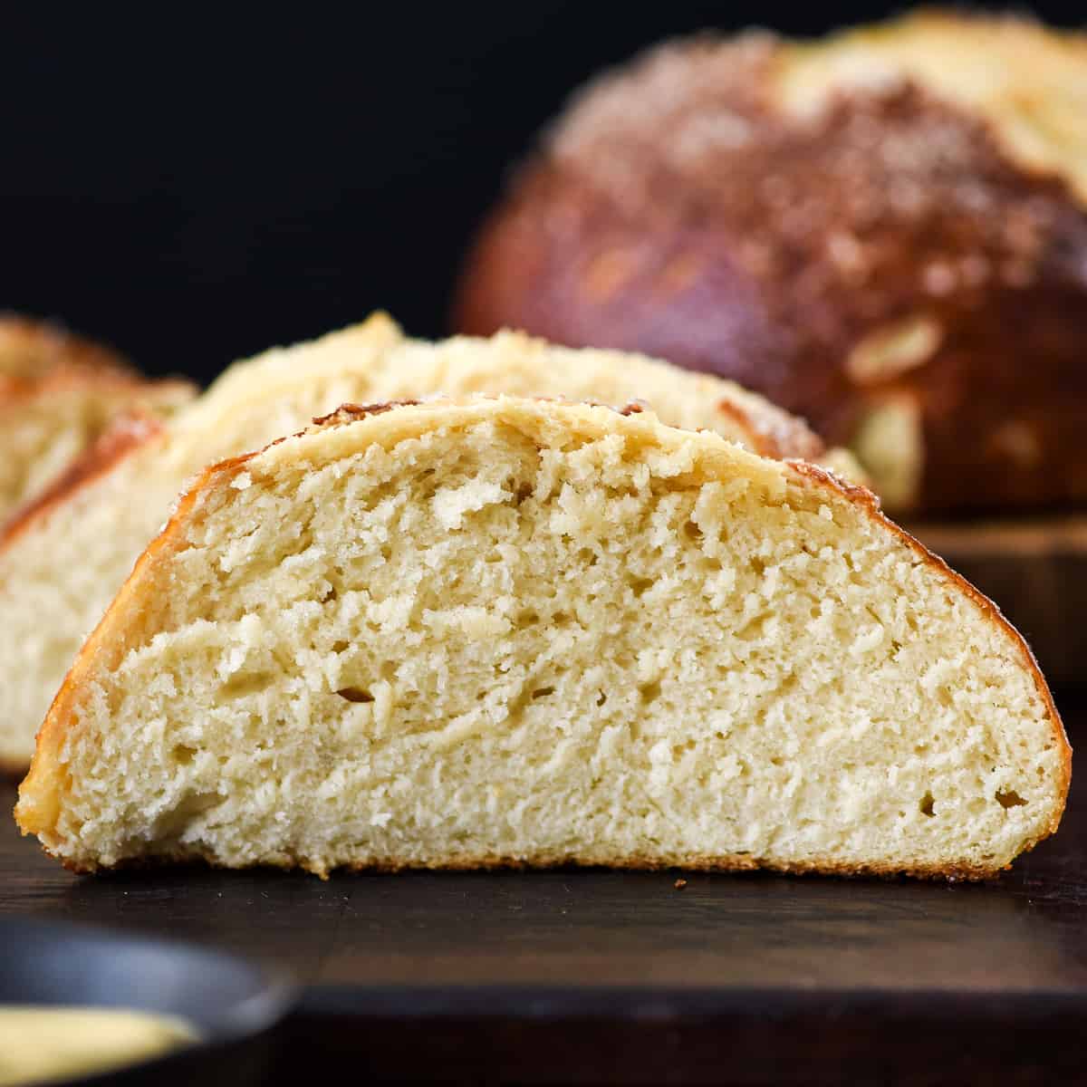 The BEST Homemade Pretzel Bread (or Pretzel Rolls) recipe ever. Seriously, once you make this you will never be able to eat store-bought pretzel bread again! It's dense, soft, chewy, buttery, salty and irresistibly delicious. Up close front view of a slice of homemade pretzel bread