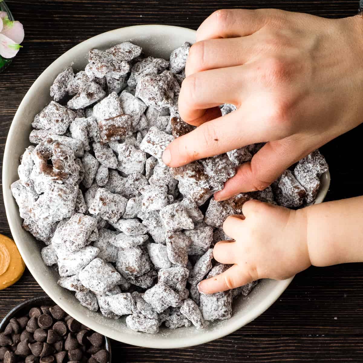 The Best Puppy Chow Recipe (AKA: Muddy Buddies) EVER! Only 4 ingredients (no butter) and a few minutes results in an irresistible dessert loaded with chocolate and peanut butter! The perfect sweet treat to feed a crowd! Overhead view of a bowl of the best puppy chow recipe in a bowl