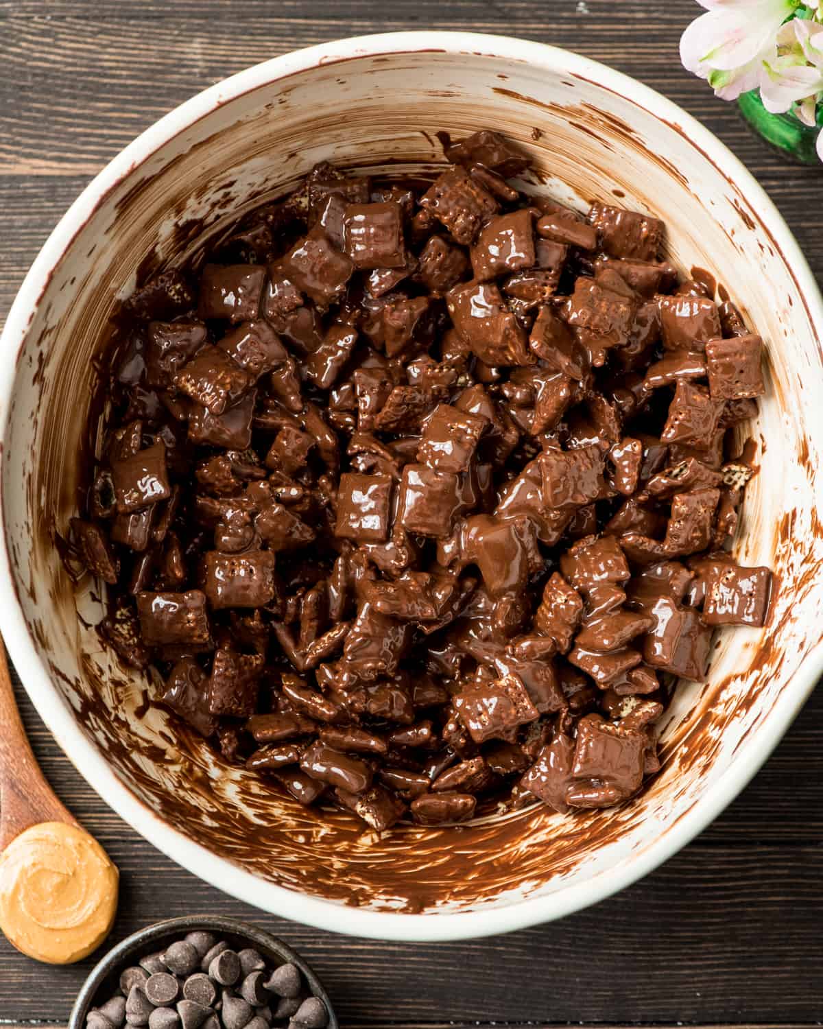 The Best Puppy Chow Recipe (AKA: Muddy Buddies) EVER! Only 4 ingredients (no butter) and a few minutes results in an irresistible dessert loaded with chocolate and peanut butter! The perfect sweet treat to feed a crowd! Overhead photo showing how to make muddy buddies (puppy chow) - peanut butter chocolate mixture stirred onto cereal
