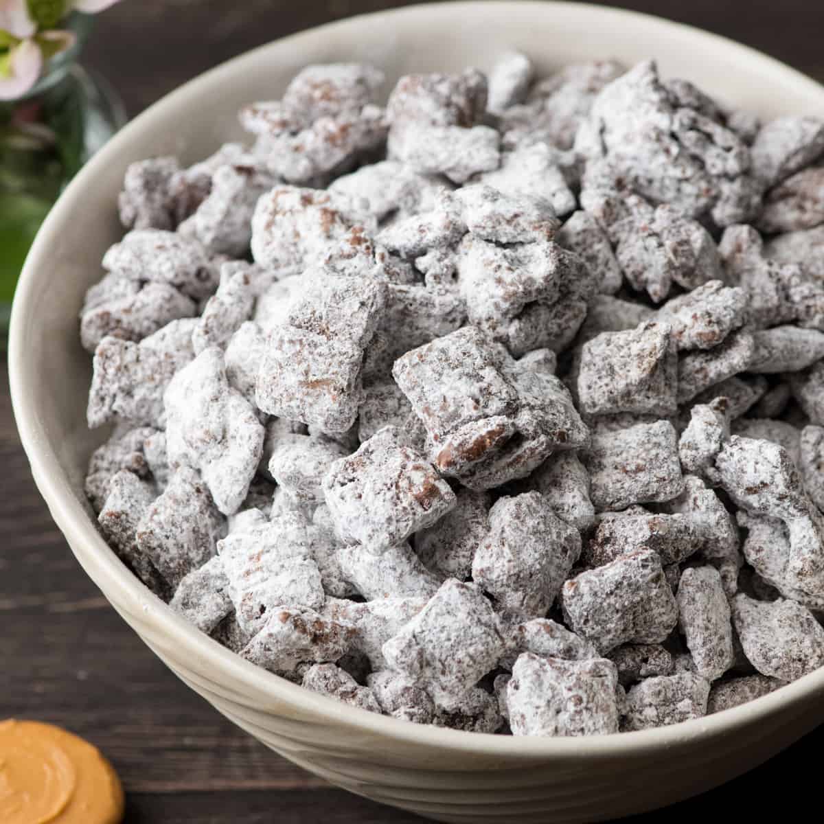 The Best Puppy Chow Recipe (AKA: Muddy Buddies) EVER! Only 4 ingredients (no butter) and a few minutes results in an irresistible dessert loaded with chocolate and peanut butter! The perfect sweet treat to feed a crowd! Side view of a bowl of the best puppy chow recipe