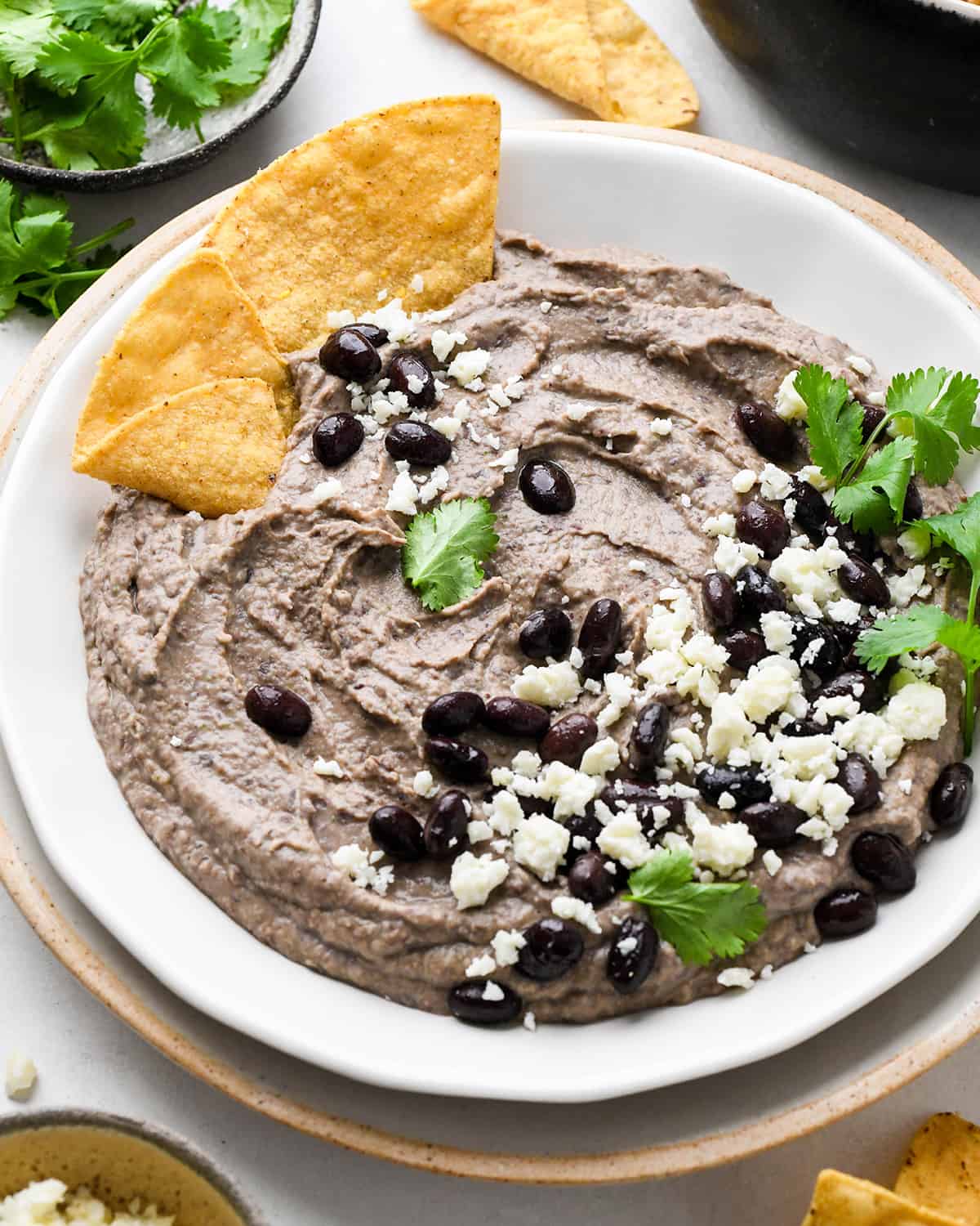 a bowl of Black Bean Dip garnished with cilantro. black beans, cheese and chips