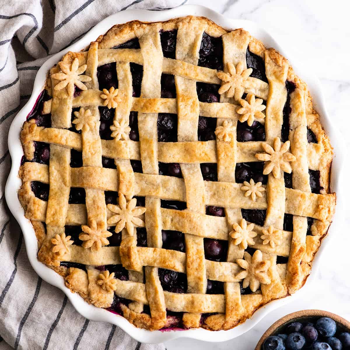 This is the best homemade Blueberry Pie Recipe you'll ever make! It's made from scratch with a fresh blueberry pie filling and NO cornstarch, and includes step-by-step instructions and photos! overhead view of a baked blueberry pie with a lattice crust