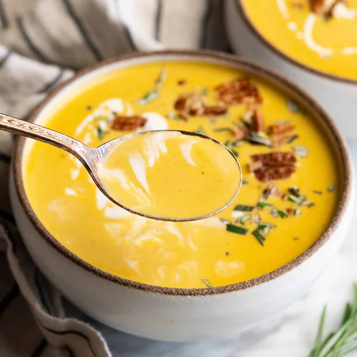 This is the Best Butternut Squash Soup Recipe ever! Celery, onion and carrots give this squash soup a beautiful depth of flavor. It's silky-smooth and perfectly sweet with a touch of fall spices. This butternut soup is easy to make in one pot with either an immersion blender or standard blender. Up close photo of a spoonful of butternut squash soup