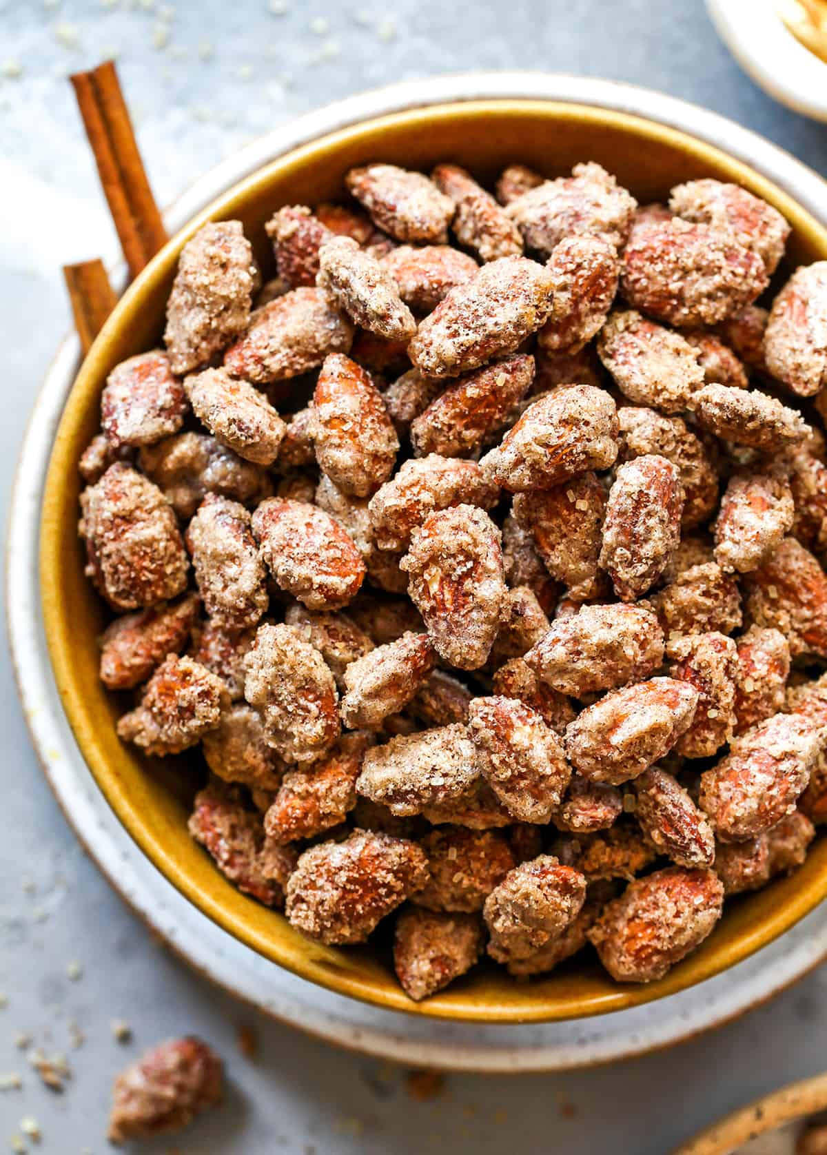 This Candied Almonds Recipe is easy to make with just 6 ingredients. These cinnamon roasted almonds are even more delicious than the nuts you can get at the mall or fair, and they're freezer-friendly so you can make a batch and enjoy them for months as a snack, on top of salads, etc. overhead view of a bowl of candied almonds