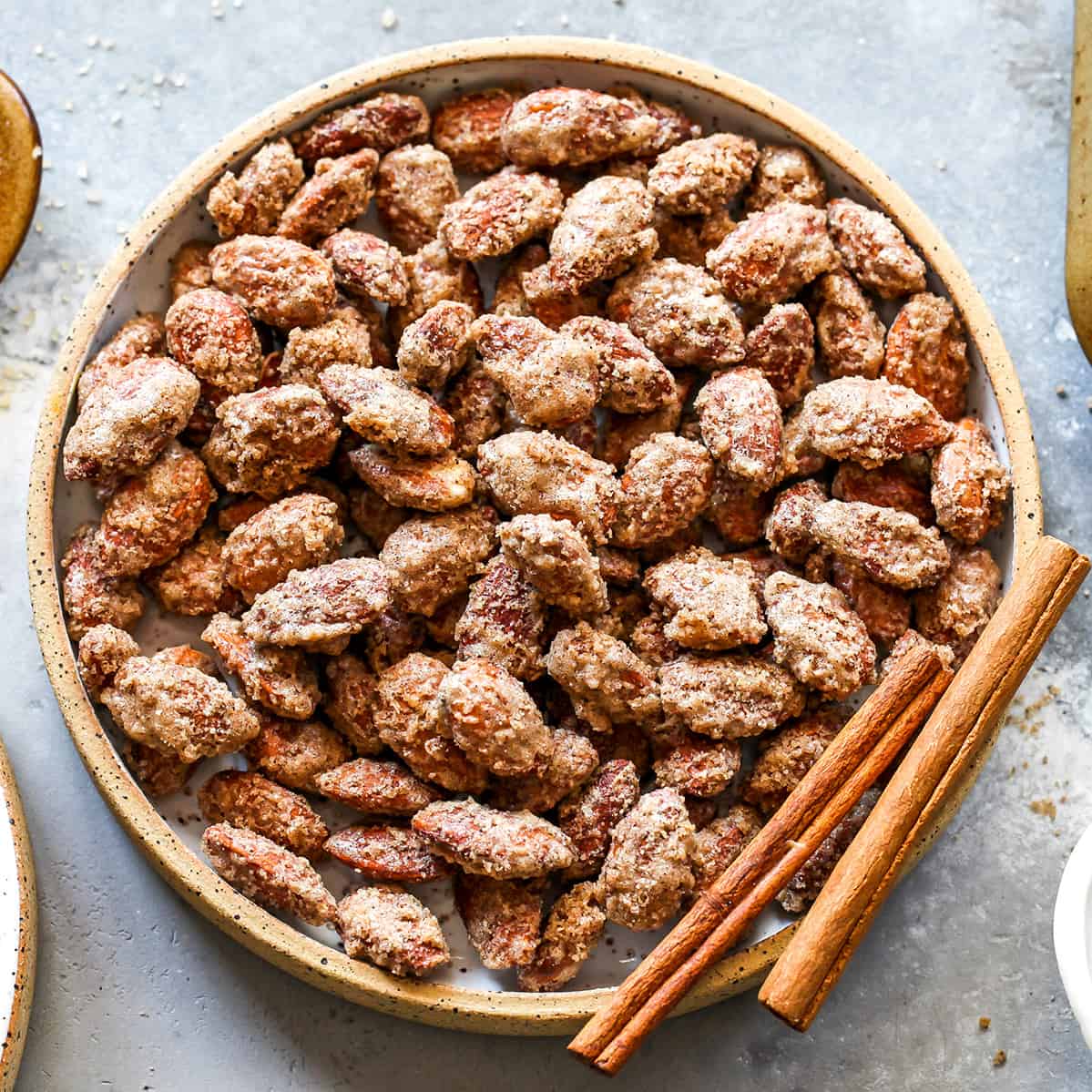 This Candied Almonds Recipe is easy to make with just 6 ingredients. These cinnamon roasted almonds are even more delicious than the nuts you can get at the mall or fair, and they're freezer-friendly so you can make a batch and enjoy them for months as a snack, on top of salads, etc. overhead view of a bowl of candied almonds