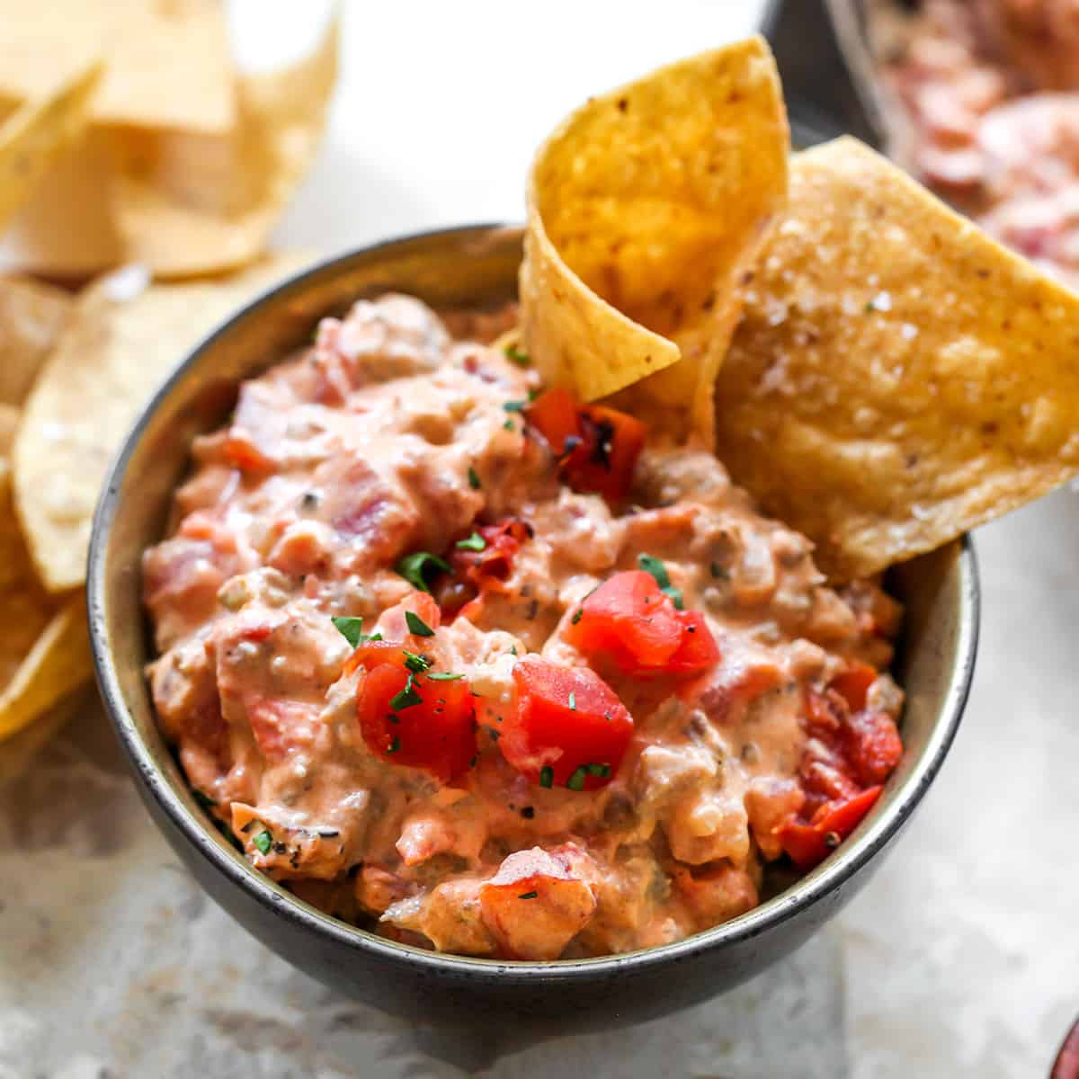 This cream cheese sausage dip is an easy appetizer made with 8 ingredients, in one skillet in 20 minutes. You can easily adjust the spice to make it mild or hot! Serve it with chips, crackers, or veggies for a delicious, low-carb, warm appetizer that will be the hit of any party. bowl of Cream Cheese Sausage Dip with chips