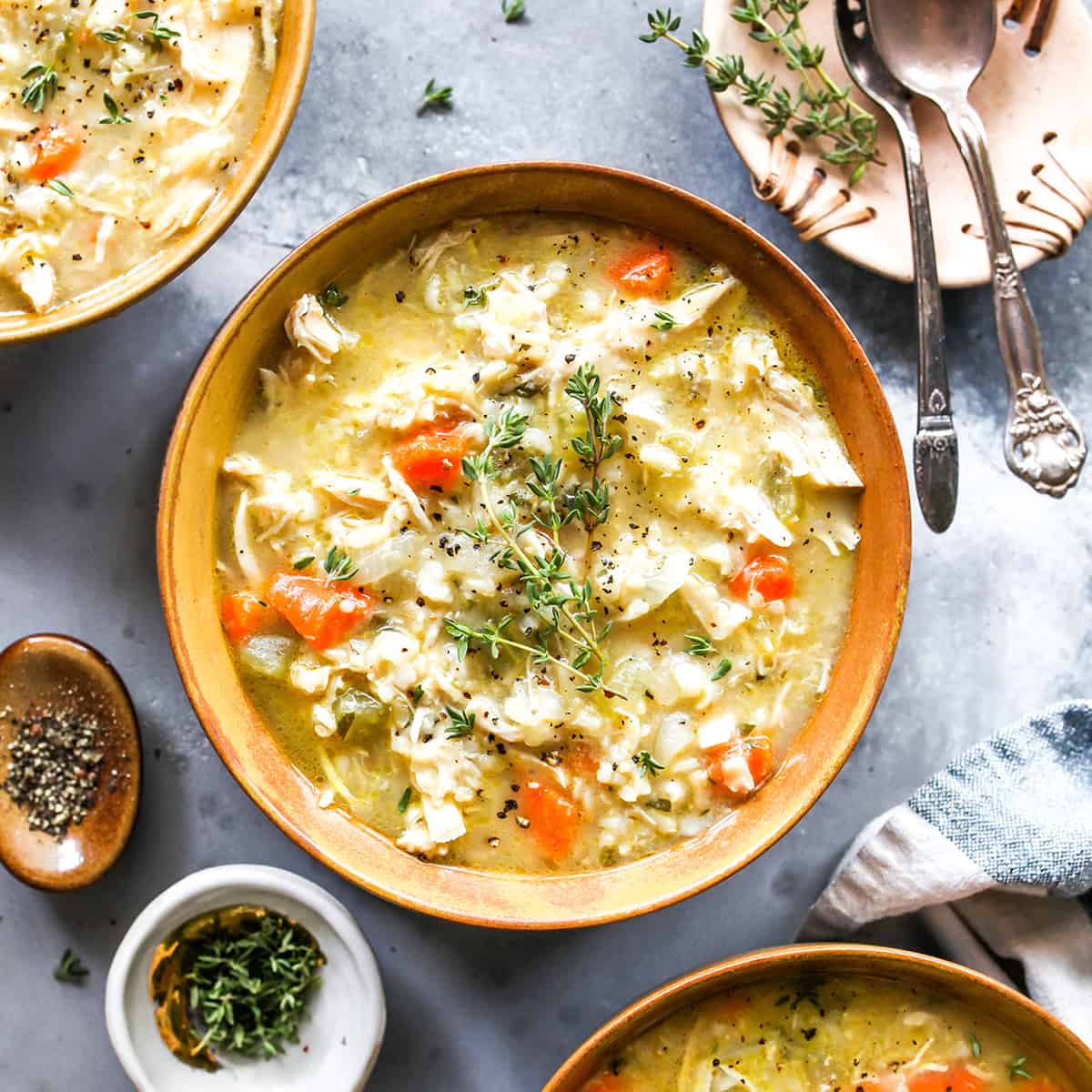 This Chicken and Rice Soup is flavorful, hearty, healthy and it's made in one pot in under an hour! Chicken and wild rice soup is a perfect meal for busy, chilly nights, it makes great leftovers & freezes well too! overhead view of a bowl of chicken and rice soup with fresh herbs