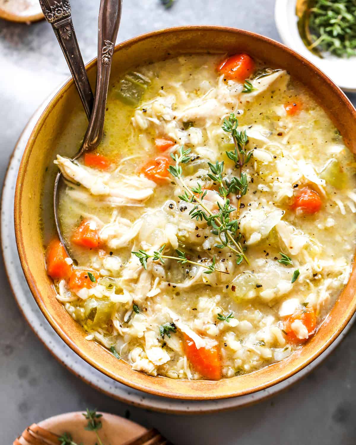 This Chicken and Rice Soup is flavorful, hearty, healthy and it's made in one pot in under an hour! Chicken and wild rice soup is a perfect meal for busy, chilly nights, it makes great leftovers & freezes well too! overhead photo of chicken and wild rice soup in a bowl with fresh herbs