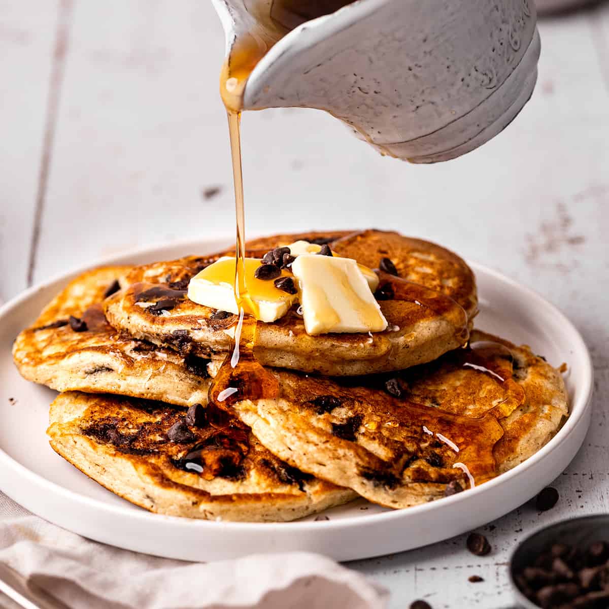syrup being poured over 4 Chocolate Chip Pancakes on a palte