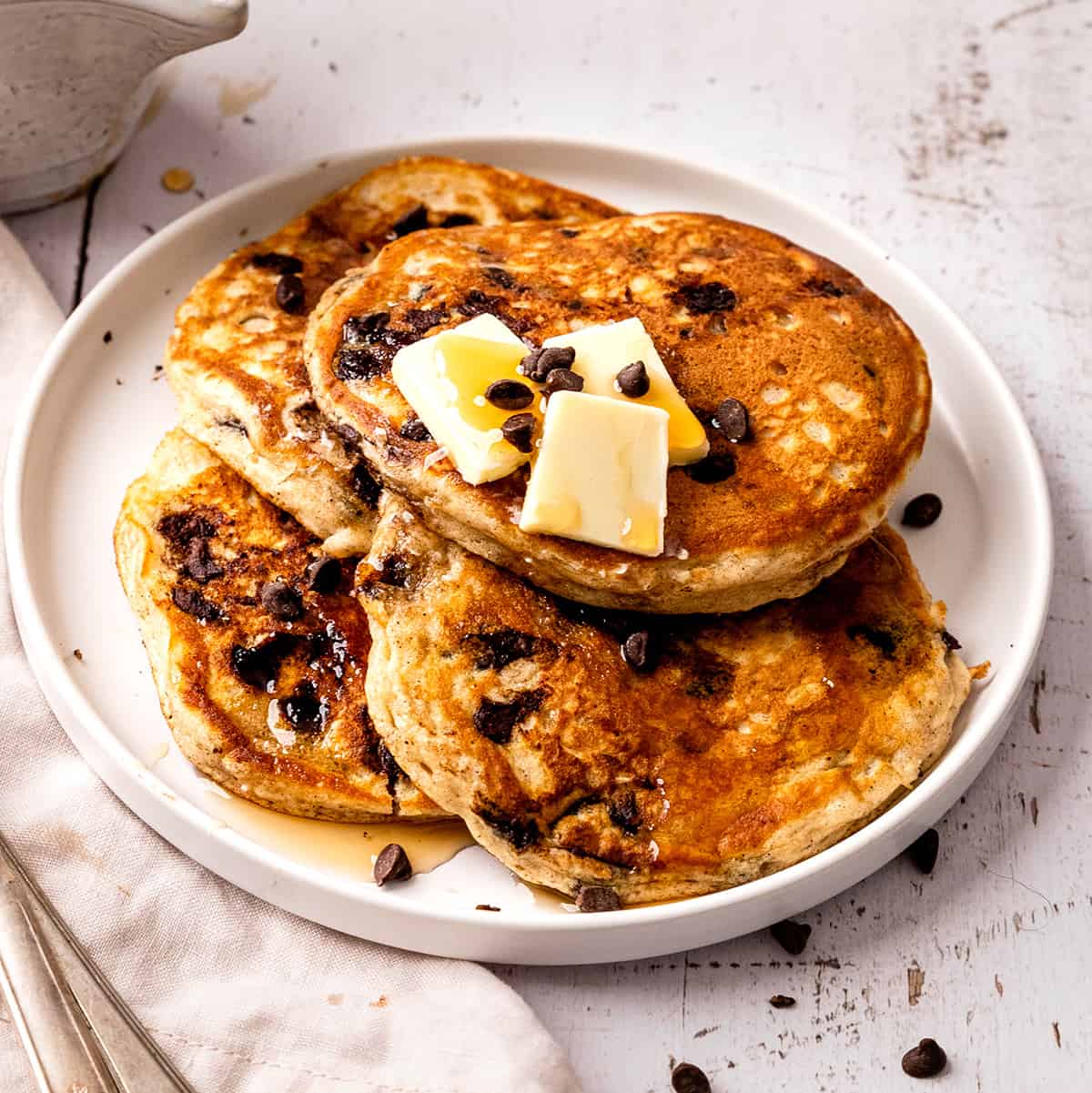 4 Chocolate Chip Pancakes on a plate with butter and syrup