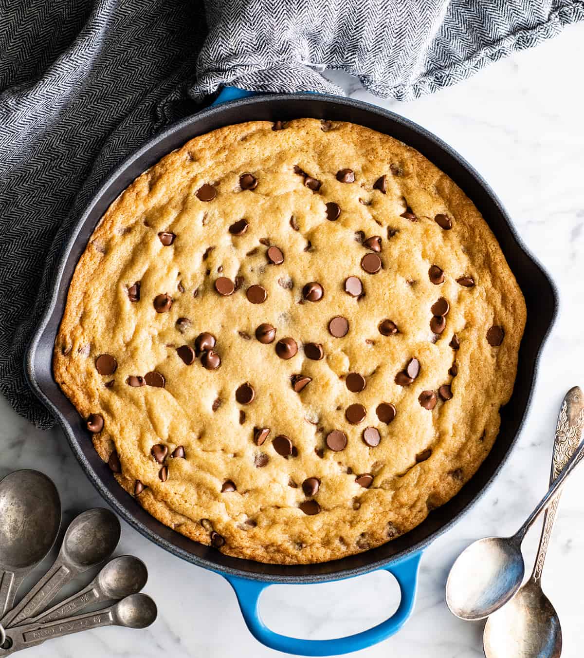 The BEST Chocolate Chip Skillet Cookie recipe! This ooey gooey, warm & melty skillet cookie (AKA: Pizookie) is completely irresistible. It's like eating warm cookie dough topped with vanilla ice cream, better than any restaurant version you've ever had! Plus it's easy to make & comes together in 20 minutes flat! #skilletcookie #pizookie #chocolatechipcookie #dessert #baking #joyfoodsunshine overhead view of a baked chocolate chip skillet cookie