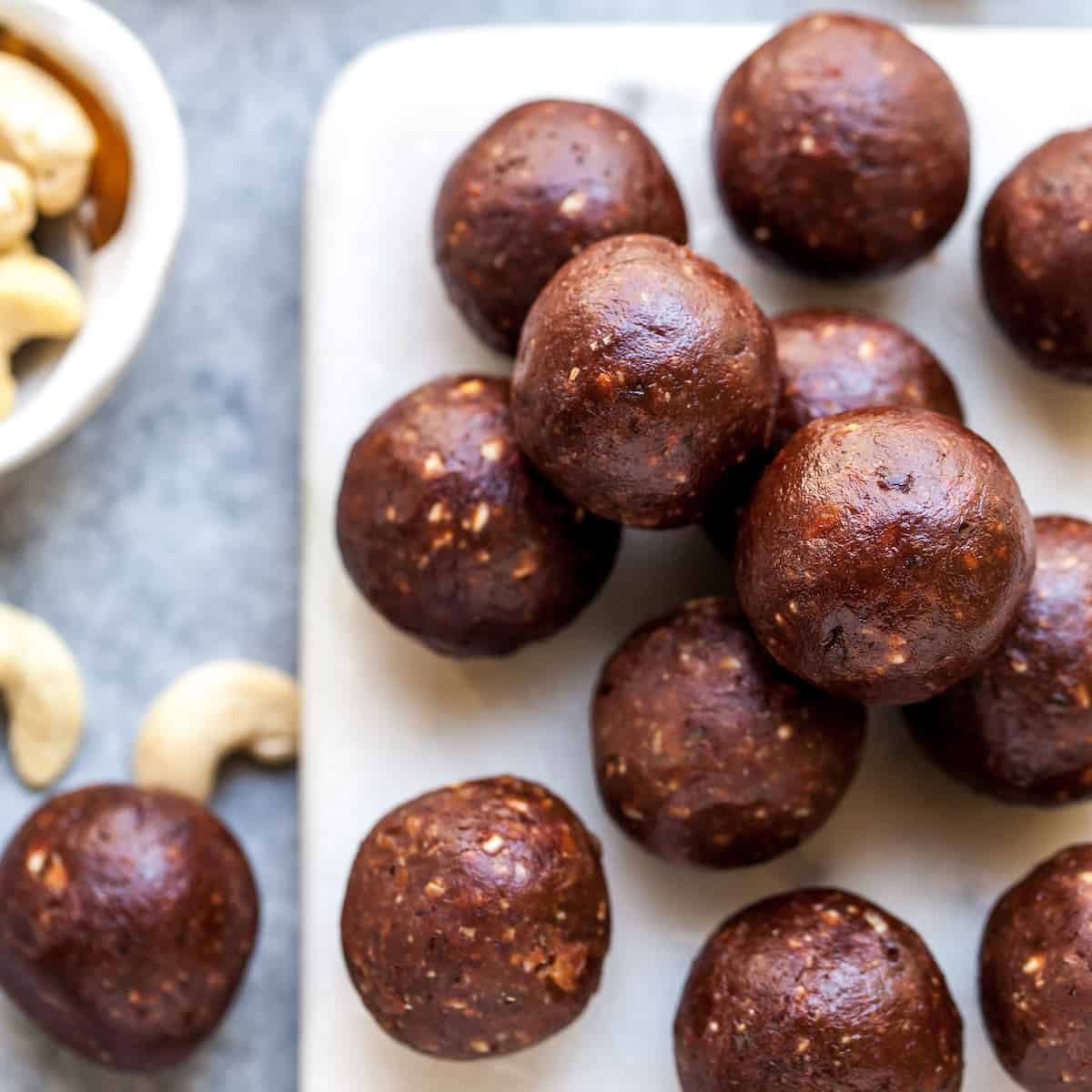 No-Bake Chocolate Date Energy Balls Recipe! These healthy energy balls are made in 5 minutes with 8 ingredients and they taste brownie bites! They are vegan, Paleo gluten-free and have no refined sugar, but you'd never know it! They're also freezer-friendly! #energyballs #energybites #vegan #paleo #snack #glutenfree #joyfoodsunshine overhead view of 13 chocolate date energy balls on a serving board