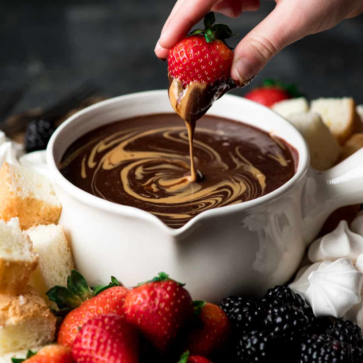 If chocolate & peanut butter is your love language, then you need to make this Dairy-Free Chocolate Peanut Butter Fondue recipe! It's the perfect desert for Valentine's Day or to serve at a Galentine's Day Brunch! #vegan #glutenfree #dairyfree #chocolate #peanutbutter #fondue #dessert a strawberry being dipped into chocolate peanut butter fondue