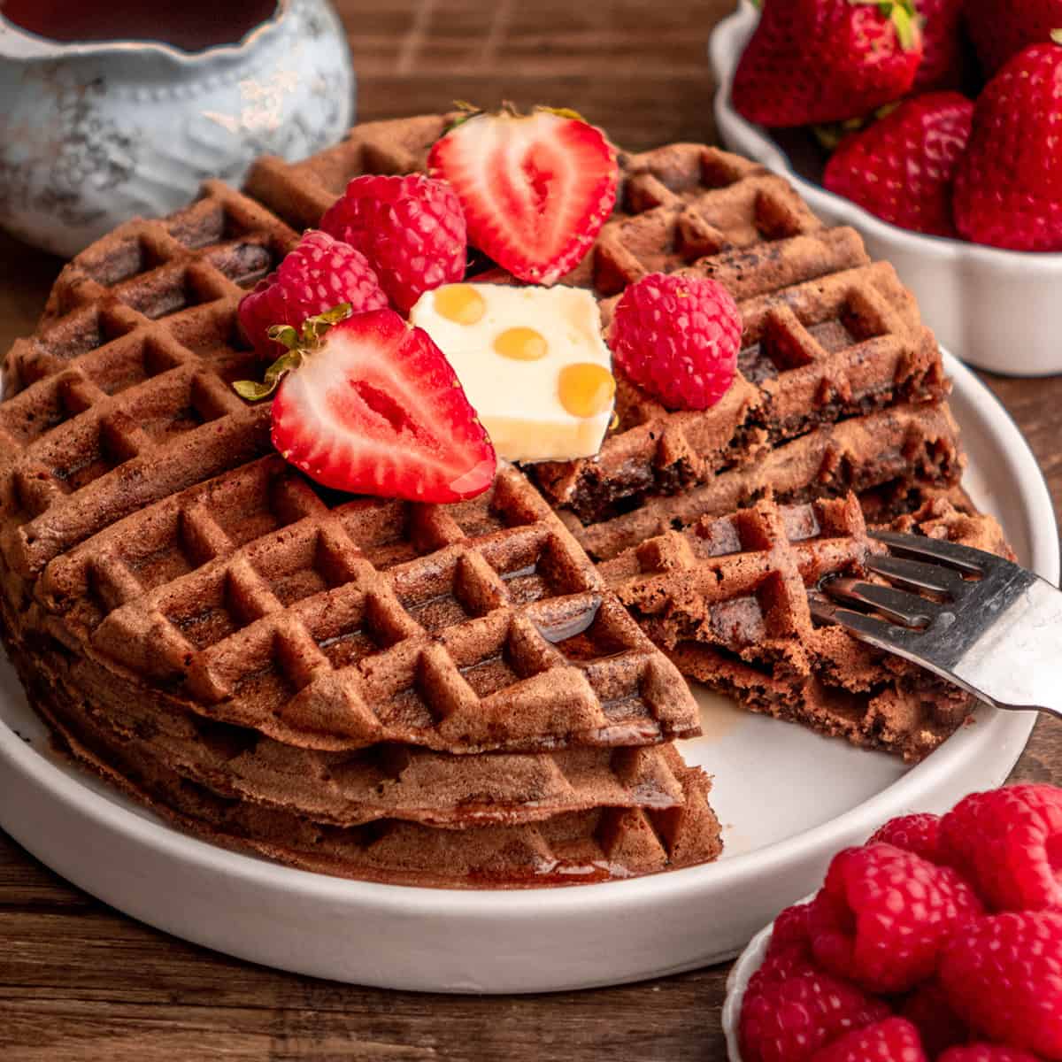 a fork taking a bite off a stack of 3 chocolate waffles
