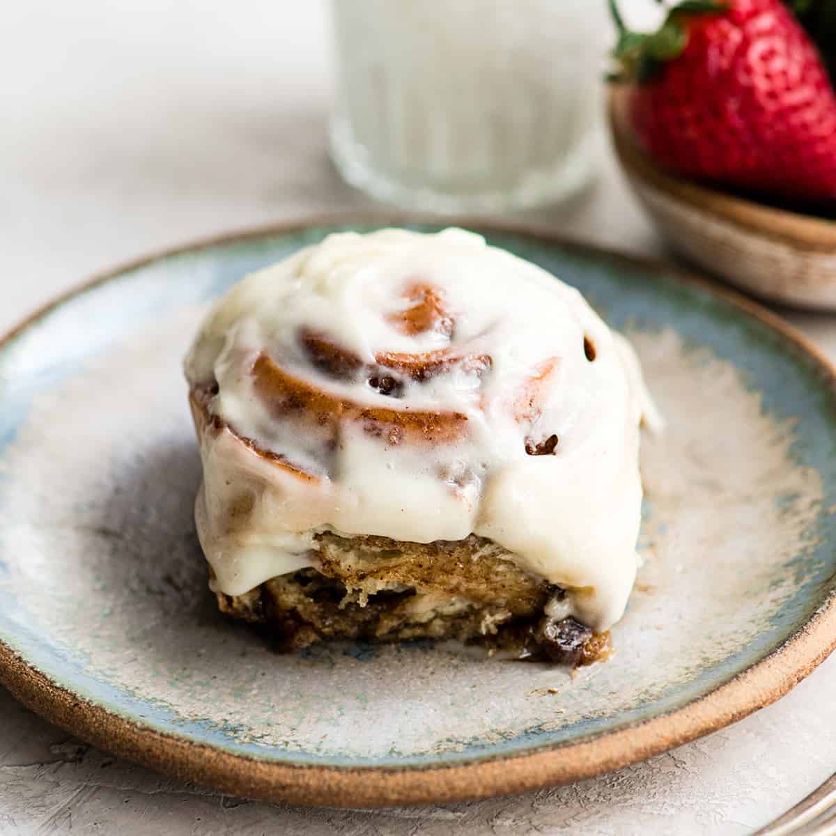 This is the Best Homemade Cinnamon Rolls Recipe EVER! These gooey cinnamon rolls are even better than Cinnabon cinnamon rolls, and are topped with a delicious cream cheese frosting! They're easy to make and can be prepared the day before and left to rise overnight in the refrigerator. front view of a cinnamon roll on a plate