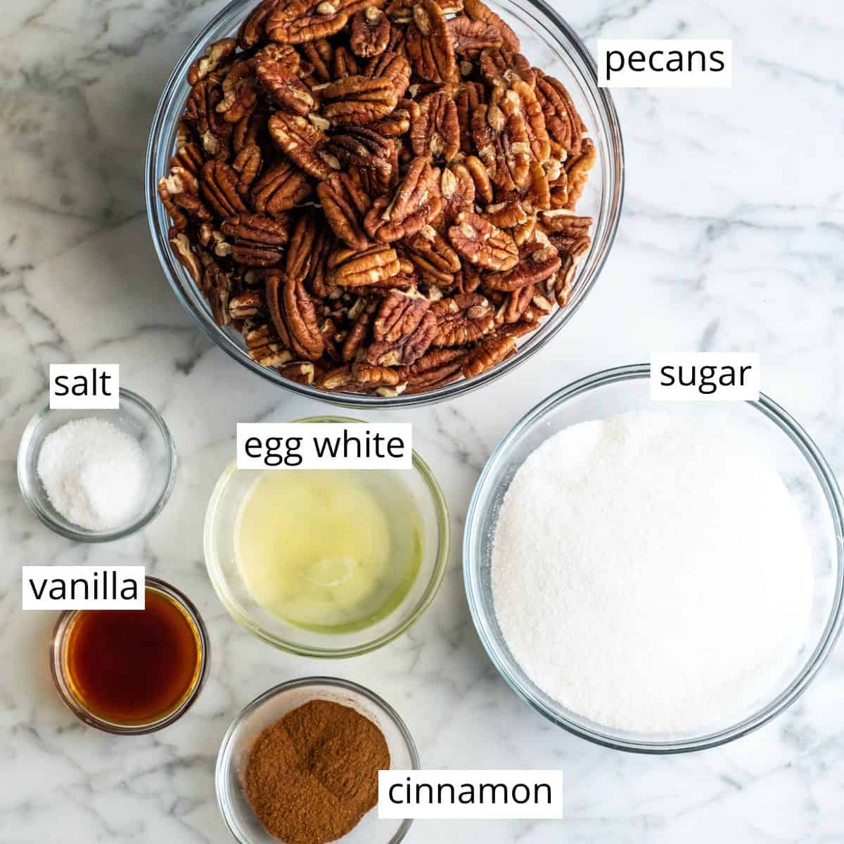 This homemade Cinnamon Sugar Pecans Recipe is made with only 6 ingredients & is WAY better than the nuts from the mall or fair! Plus, they're gluten & dairy-free & freezer-friendly! Make a batch, store them in the freezer and use as a salad topper or enjoy as a sweet snack! #glutenfree #dairyfree #cinnamonsugarnuts #pecans #snack #saladtopper #easy #homemade overhead view of the labeled ingredients in this candied cinnamon sugar pecans recipe