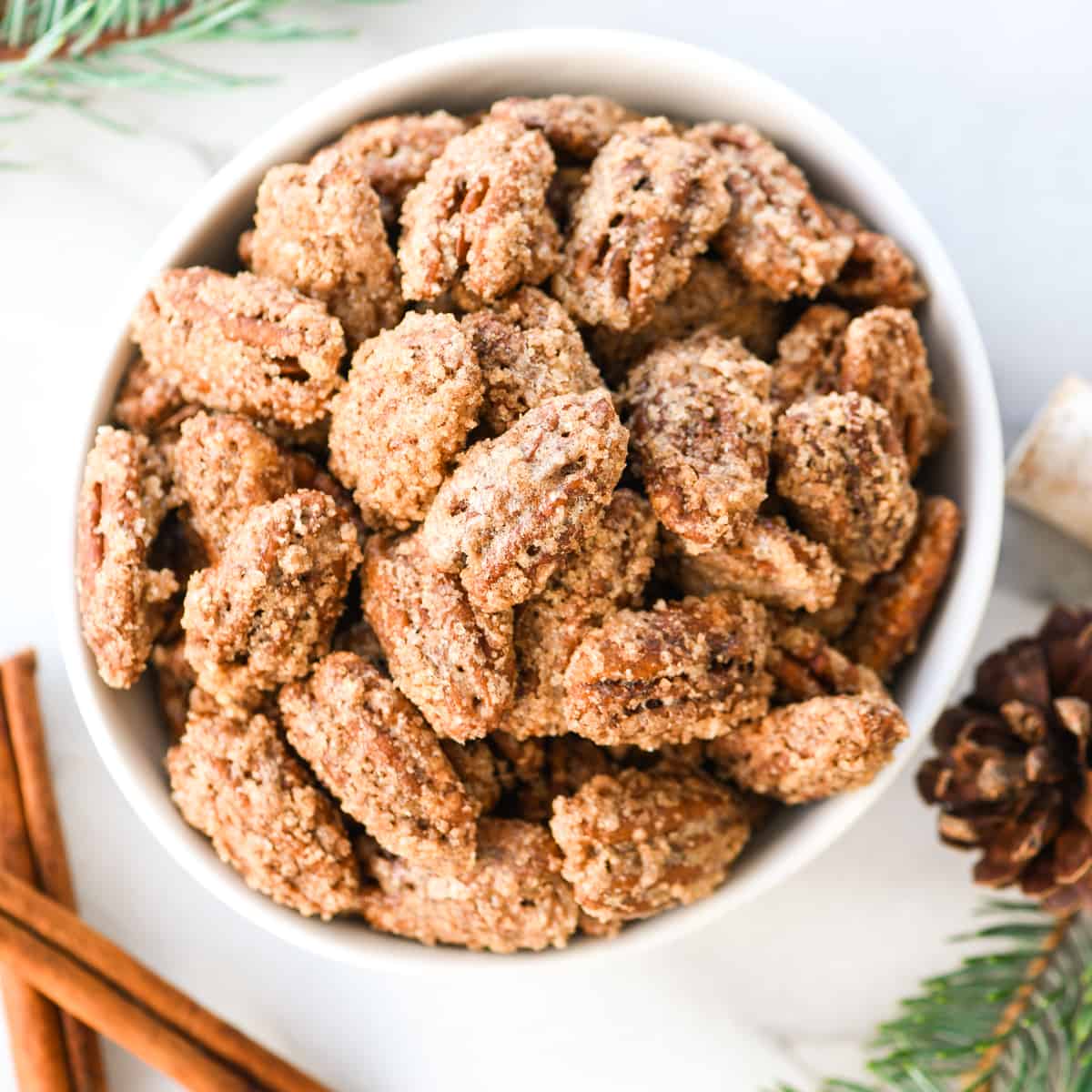 This homemade Cinnamon Sugar Pecans Recipe is made with only 6 ingredients & is WAY better than the nuts from the mall or fair! Plus, they're gluten & dairy-free & freezer-friendly! Make a batch, store them in the freezer and use as a salad topper or enjoy as a sweet snack! #glutenfree #dairyfree #cinnamonsugarnuts #pecans #snack #saladtopper #easy #homemade a bowl of candied pecans