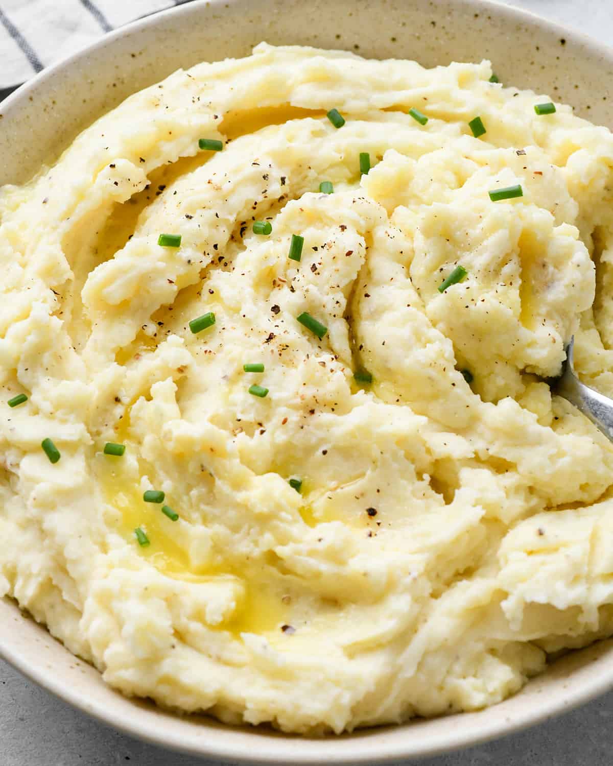 a bowl of Cream Cheese Mashed Potatoes with butter, salt, pepper and chives