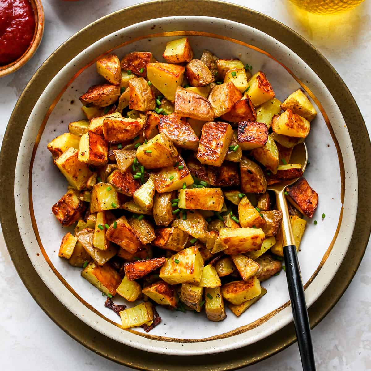 Oven Roasted Potatoes on a plate with a spoon garnished with chives