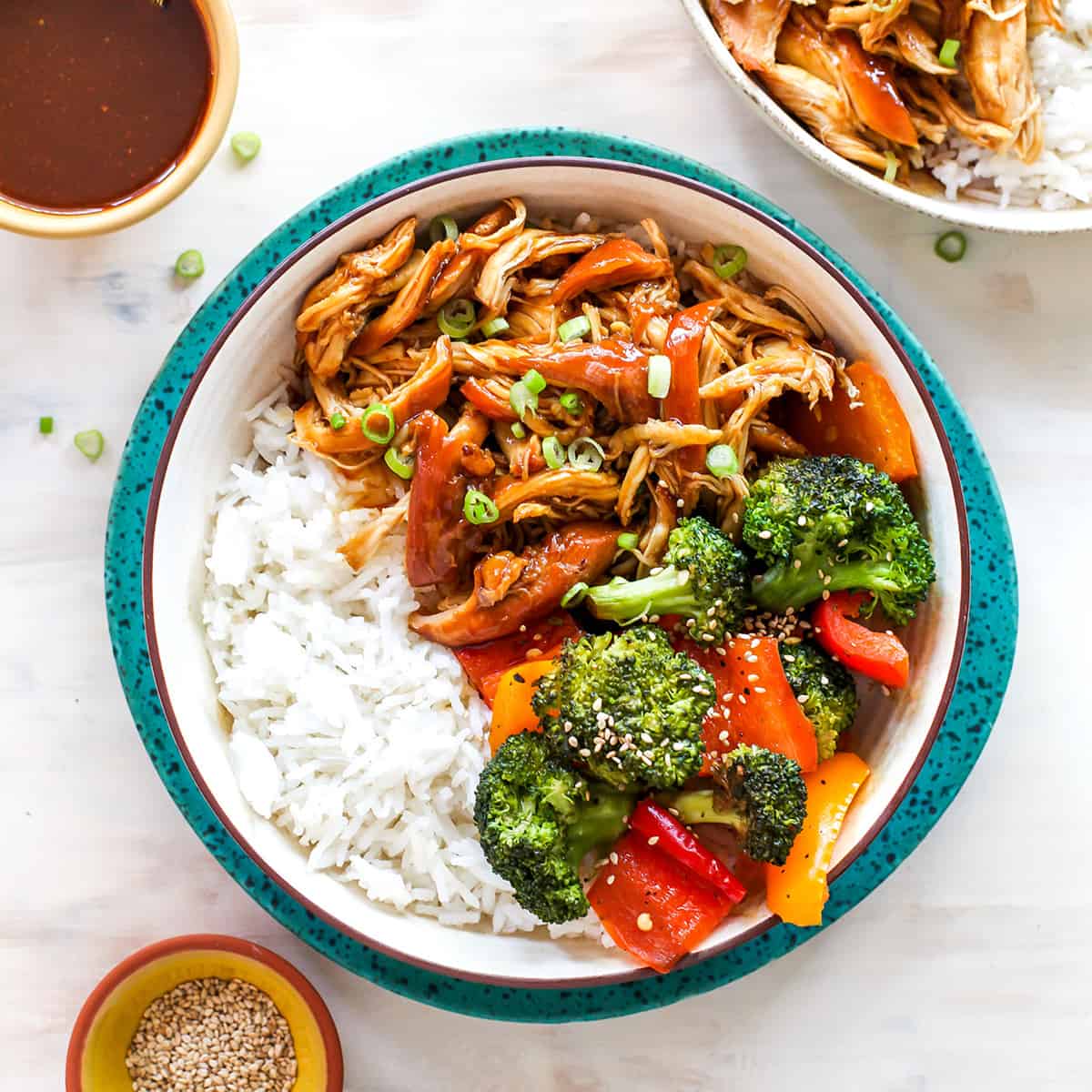 This Crockpot Teriyaki Chicken recipe is an easy recipe perfect for busy weeknights! It only takes 5 minutes to mix together, and then put it in the slow cooker to let it cook. Serve with stir-fried veggies and rice and you have a delicious and healthy meal the whole family will love! overhead view of a bowl of crockpot teriyaki chicken with veggies and rice