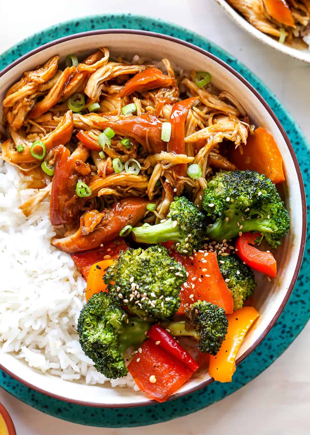 This Crockpot Teriyaki Chicken recipe is an easy recipe perfect for busy weeknights! It only takes 5 minutes to mix together, and then put it in the slow cooker to let it cook. Serve with stir-fried veggies and rice and you have a delicious and healthy meal the whole family will love! overhead view of a bowl of crockpot teriyaki chicken with veggies and rice