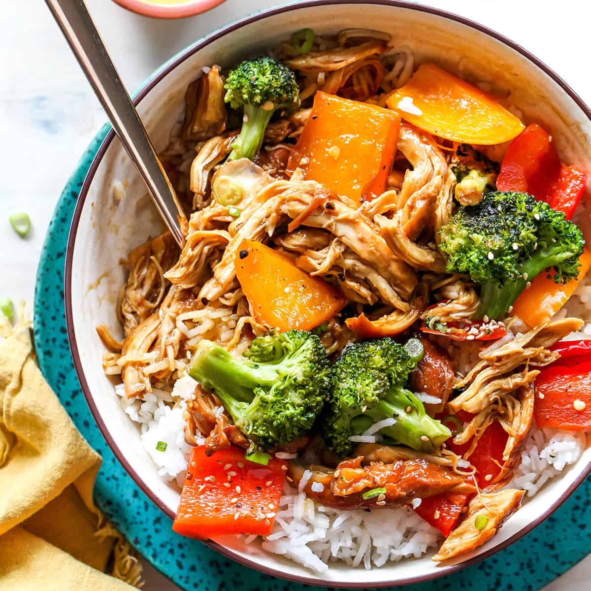 This Crockpot Teriyaki Chicken recipe is an easy recipe perfect for busy weeknights! It only takes 5 minutes to mix together, and then put it in the slow cooker to let it cook. Serve with stir-fried veggies and rice and you have a delicious and healthy meal the whole family will love! overhead view of a bowl of crockpot teriyaki chicken with veggies and rice