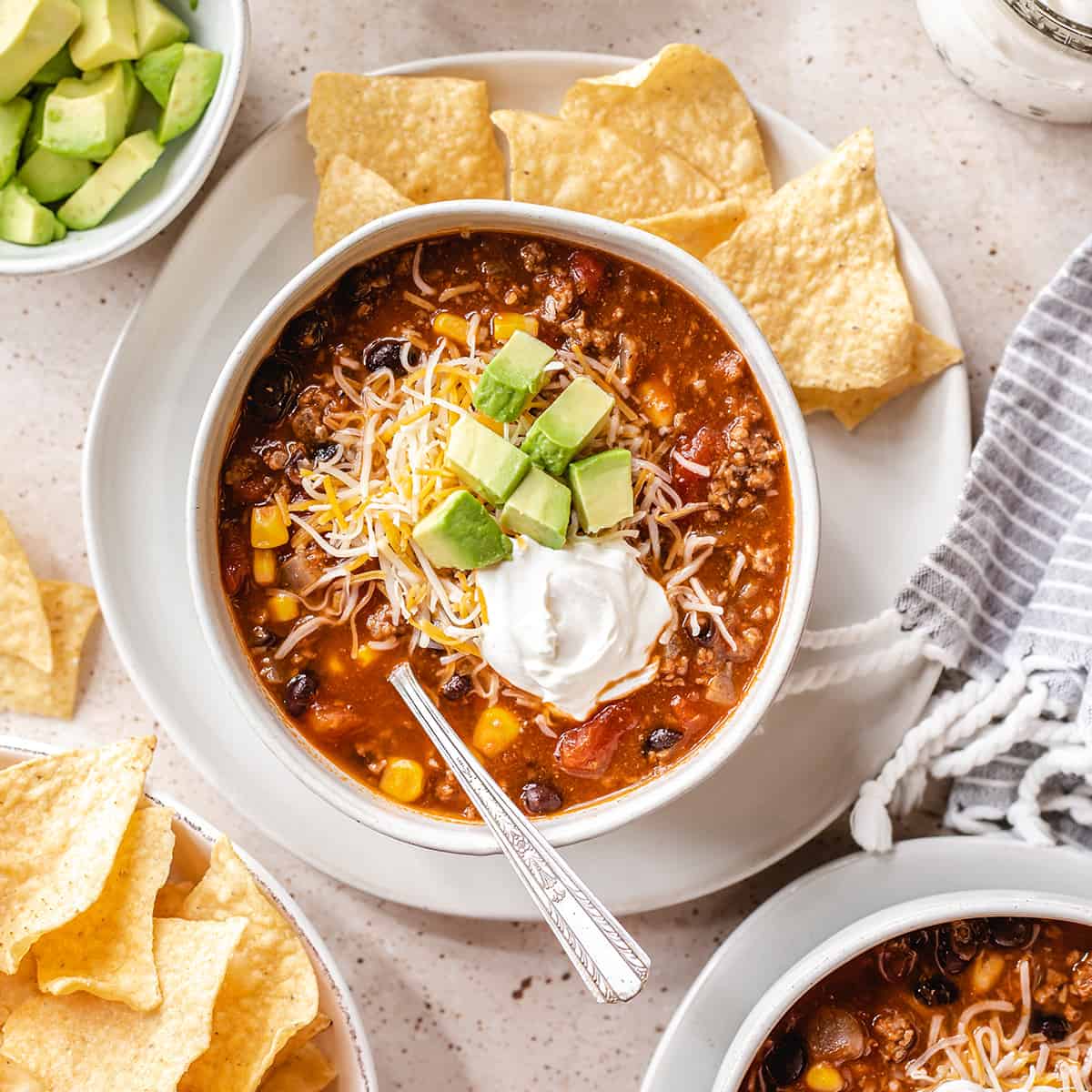 a bowl of Taco Soup topped with sour cream, avocado and cheese